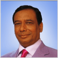 Smiling man in a suit and tie against a blue background.